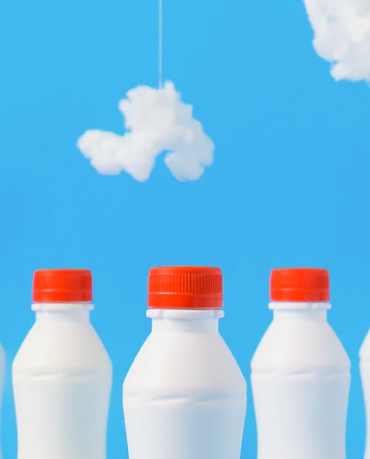 Image of milk bottles placed in front of a scene with fake clouds